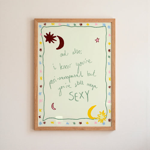 Multi coloured 'you're still sexy' print in wooden frame on white wall