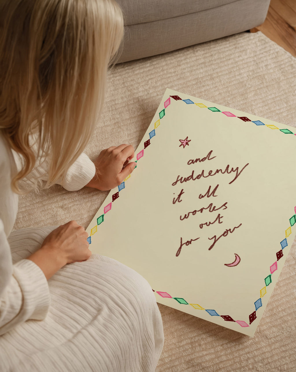 Person holding a large print with motivational text on a carpeted floor