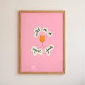 Framed pink poster with aperol spritz illustration and text on a beige wall.