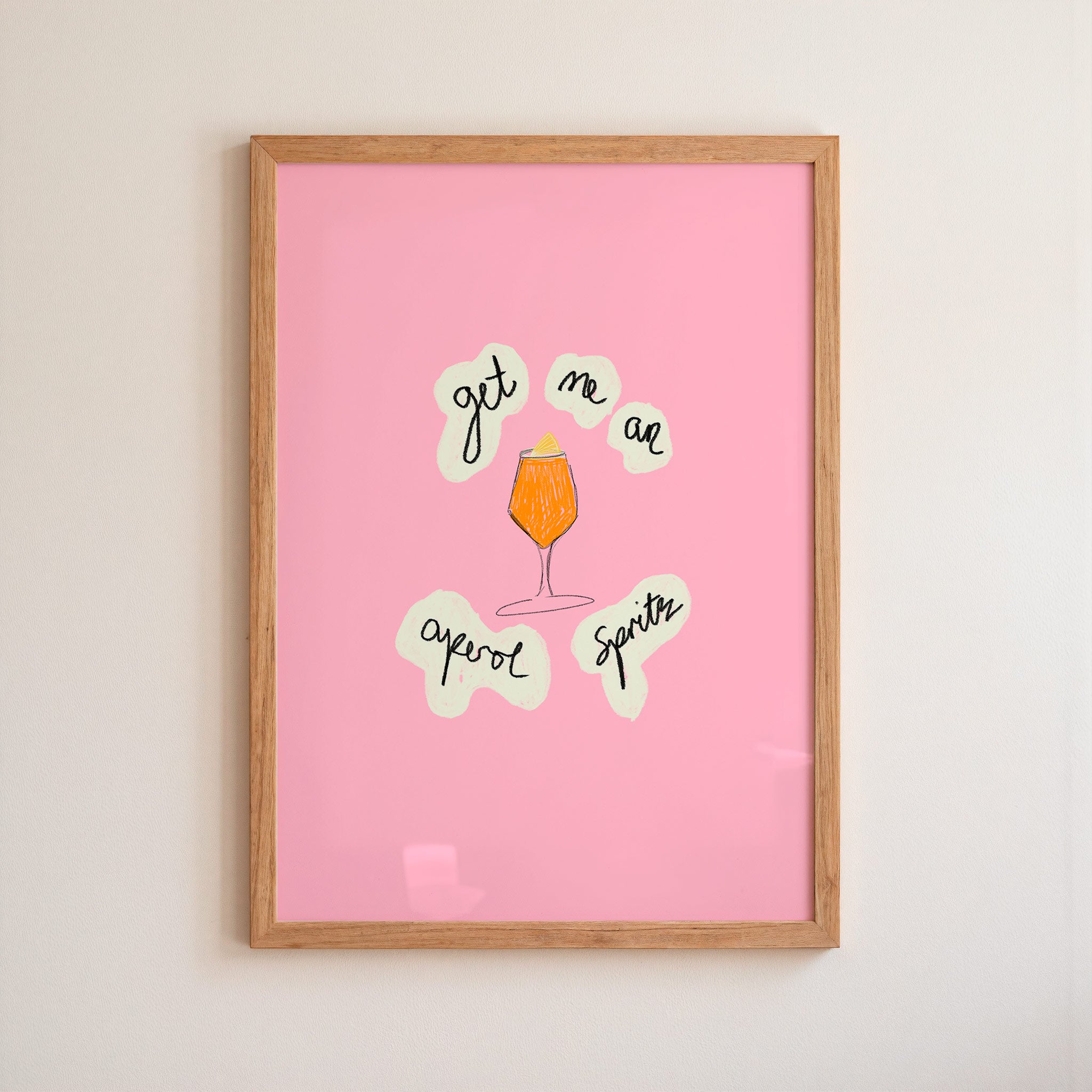 Framed pink poster with aperol spritz illustration and text on a beige wall.