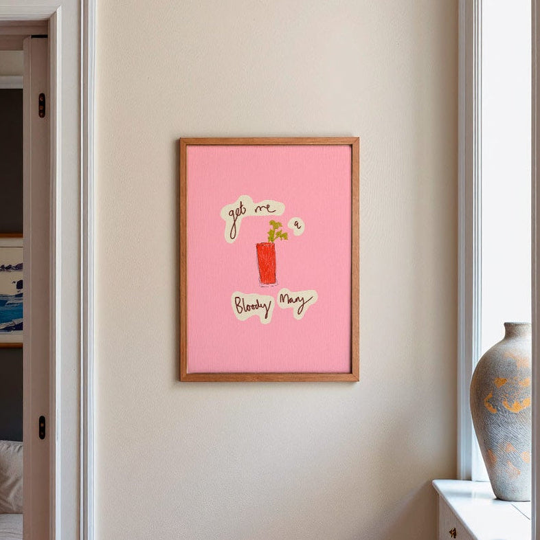 Modern kitchen with a pink framed picture on the wall, a vase of flowers on the counter, and a view into a living room.