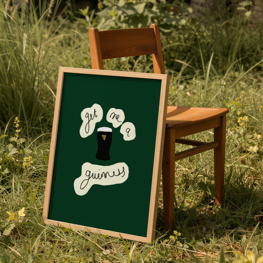 Framed green print get me a guinness on a wooden chair in a grassy outdoor setting