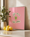 Framed pink art print with text on a surface with lemons and a plant.