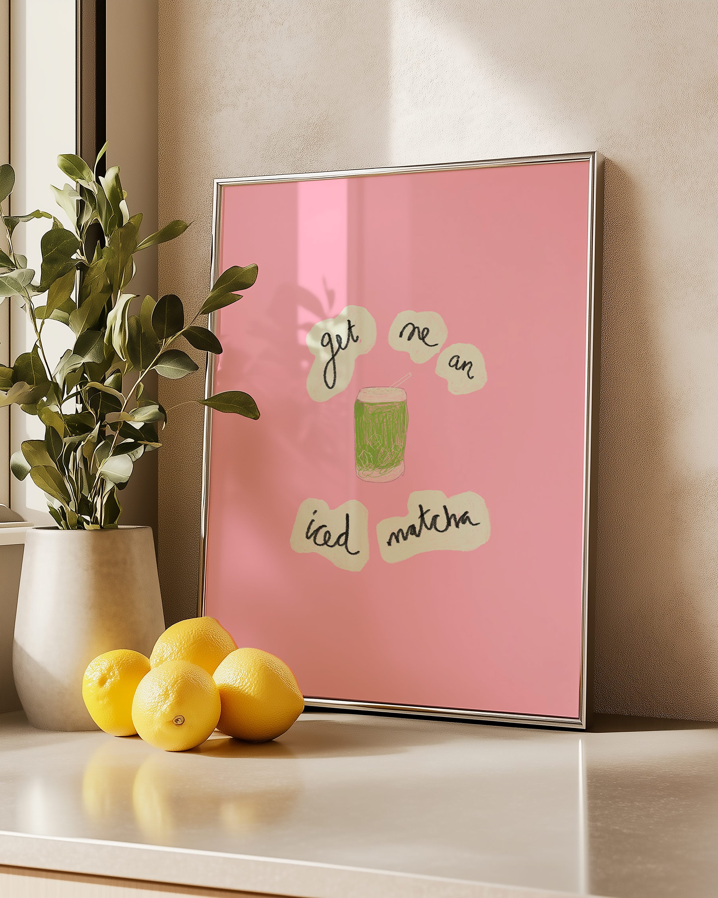 Framed pink art print with text on a surface with lemons and a plant.