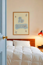 Bedroom with white bedding, wooden headboard, and framed artwork on wall.