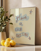Silver frame with motivational quote 'go drink a cold diet coke', lemons, and plant on a surface.