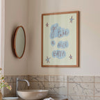 Bathroom interior with a framed quote on the wall, round mirror, and sink.