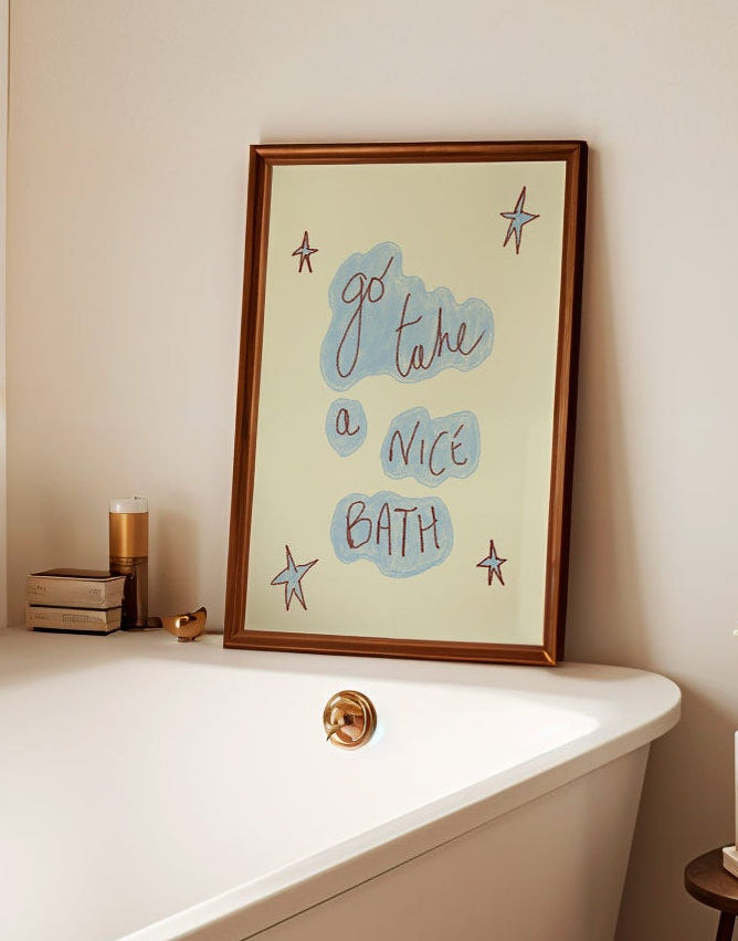 Bathroom with a bathtub, framed artwork, and small table with decor items.
