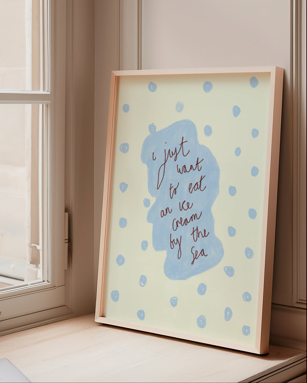 Framed artwork with blue design on a windowsill next to books
