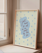 Framed artwork with blue design on a windowsill next to books