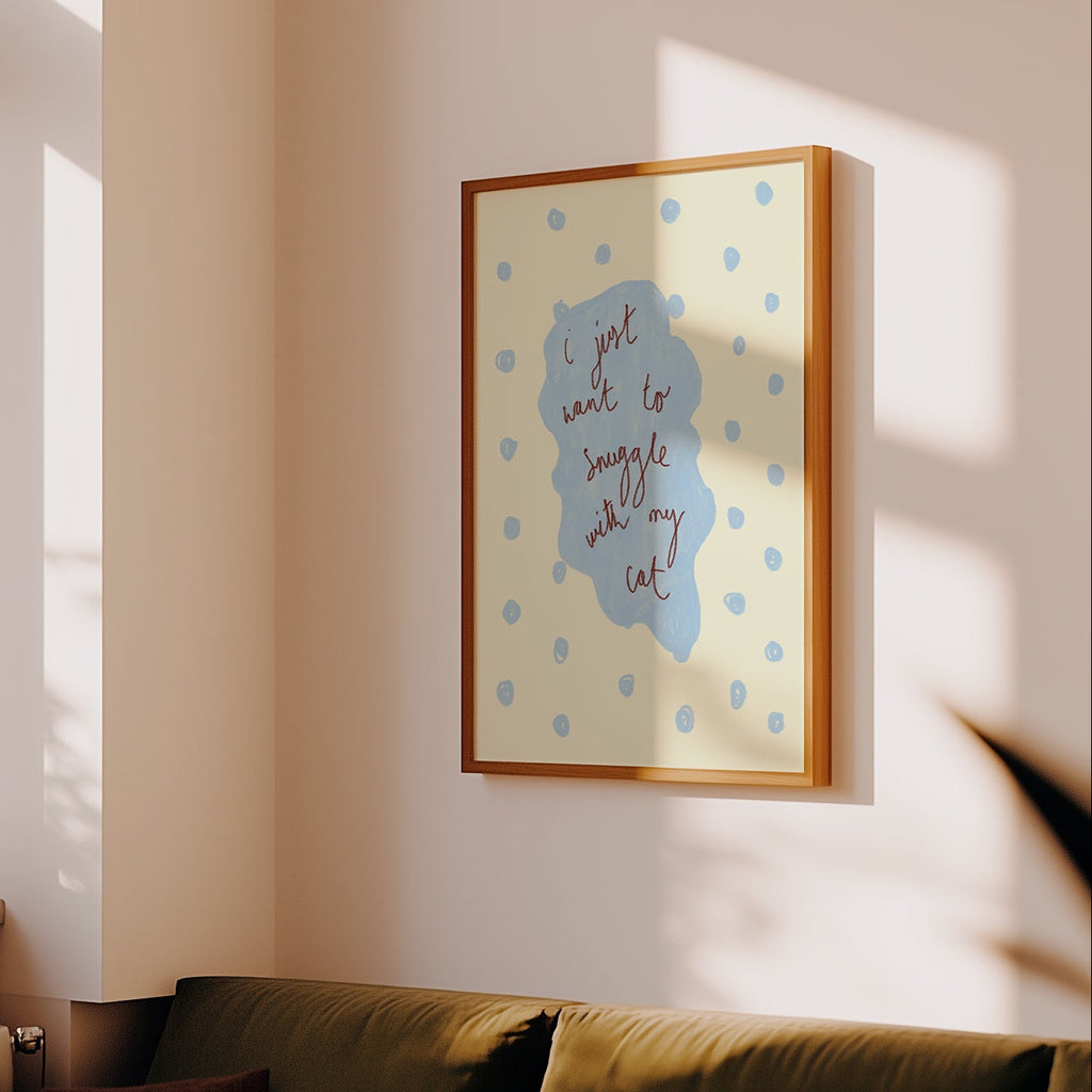 Framed artwork on a wall in a living room with a couch and window.