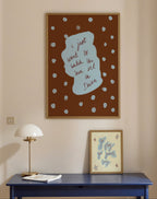 Wall art with text and abstract design on a beige wall above a blue table.