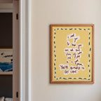 Yellow 'eat cake' print in a Modern kitchen with a blue island, white cabinets, and a view into a living room.