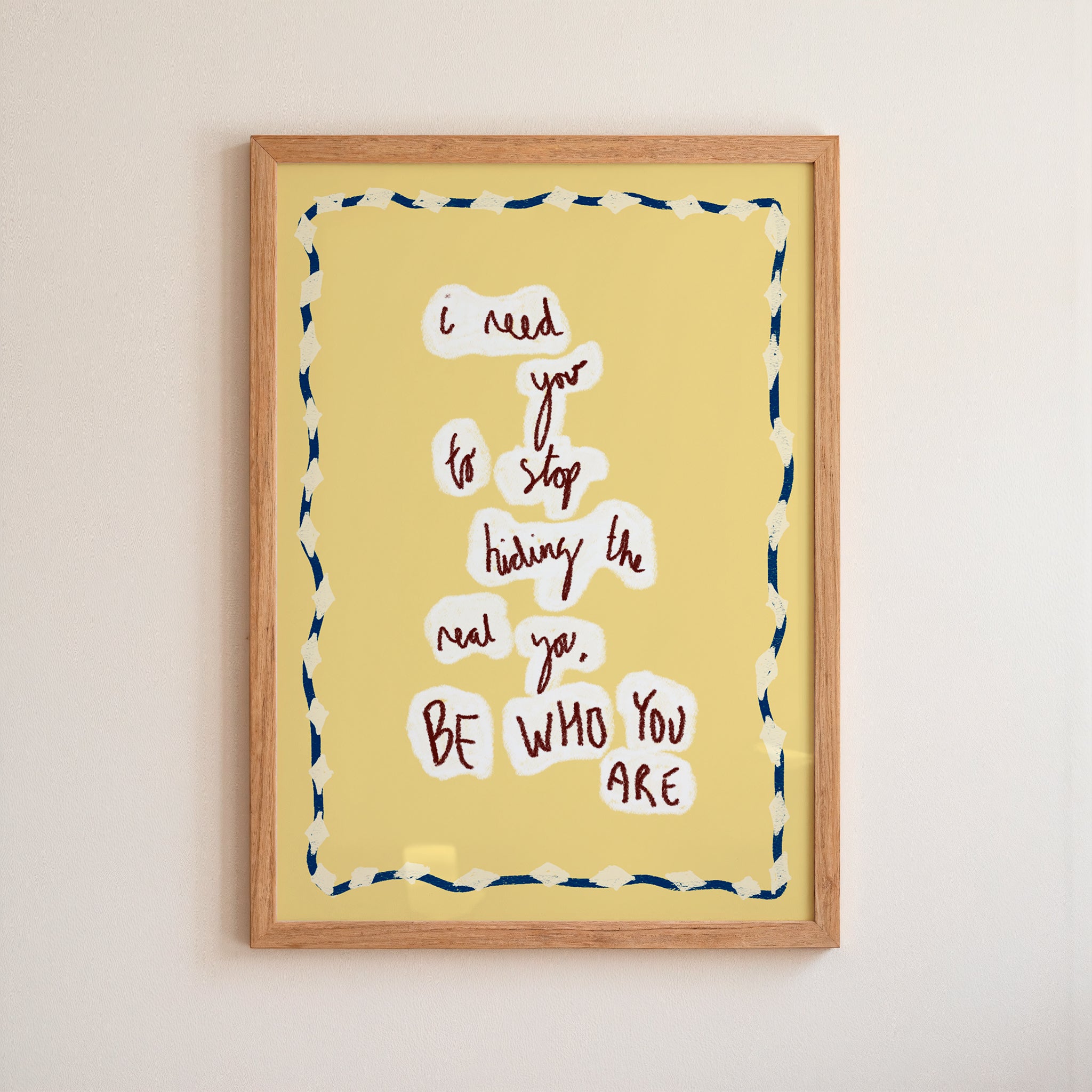 Yellow motivational 'be who you are' poster in a frame on white wall