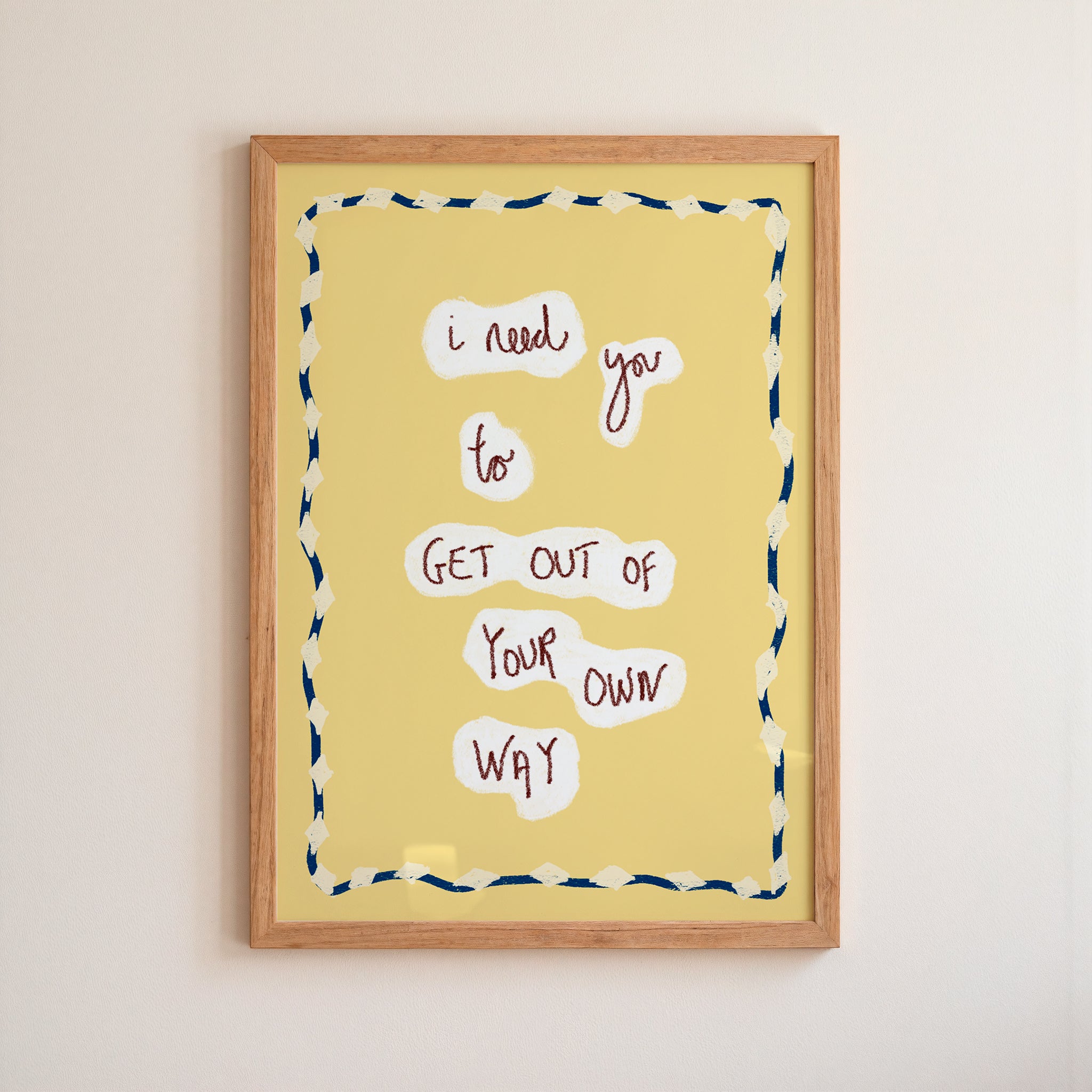 Framed yellow poster with motivational quote on a beige wall