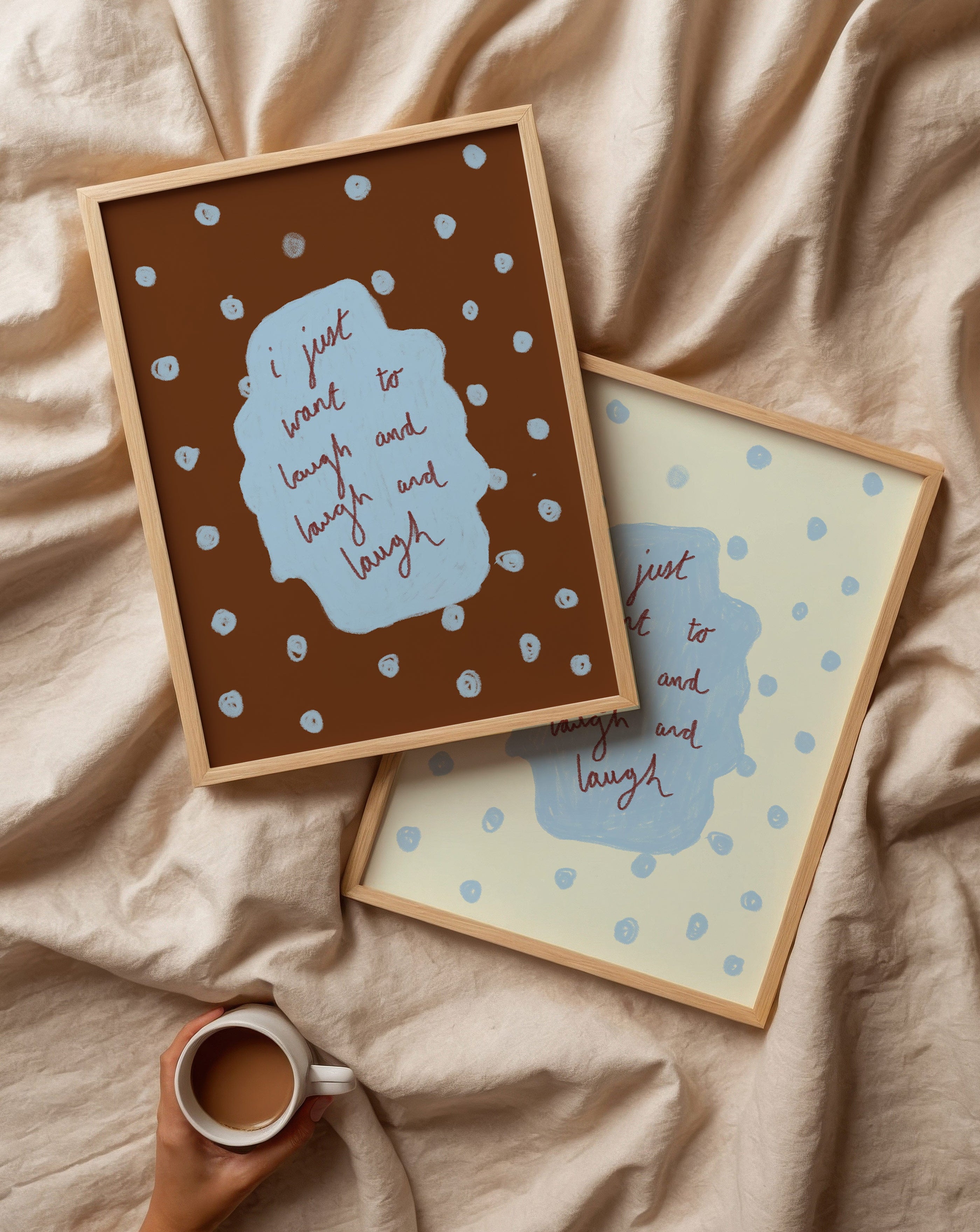 Two framed prints with polka dots and text on a beige fabric background, with a hand holding a mug.