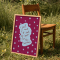 Purple and blue print with words 'i just want to read my book in the sunshine' in frame against chair outside