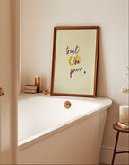 Bathroom with a bathtub, framed quote saying trust the process, and small table with decor items.