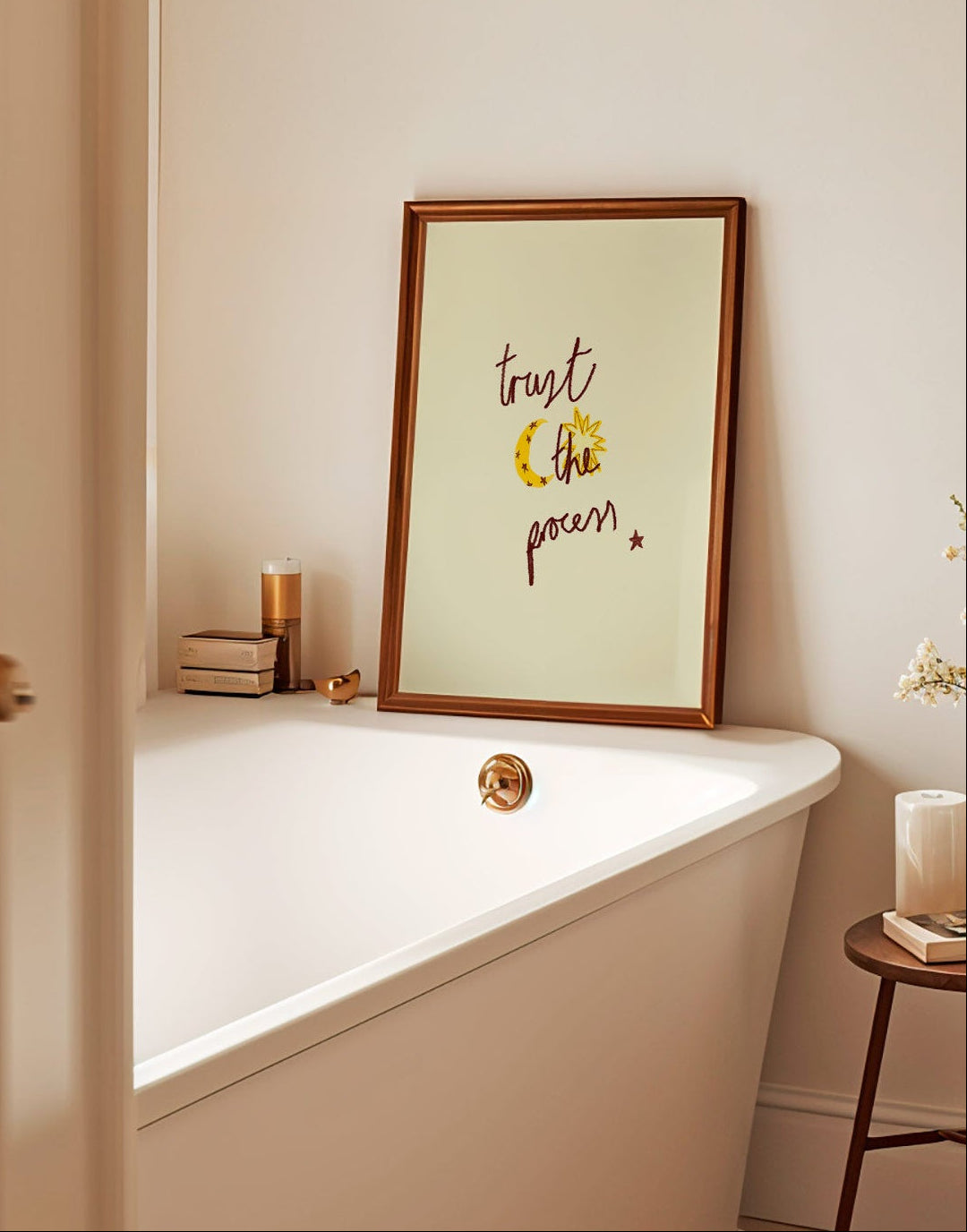Bathroom with a bathtub, framed quote saying trust the process, and small table with decor items.