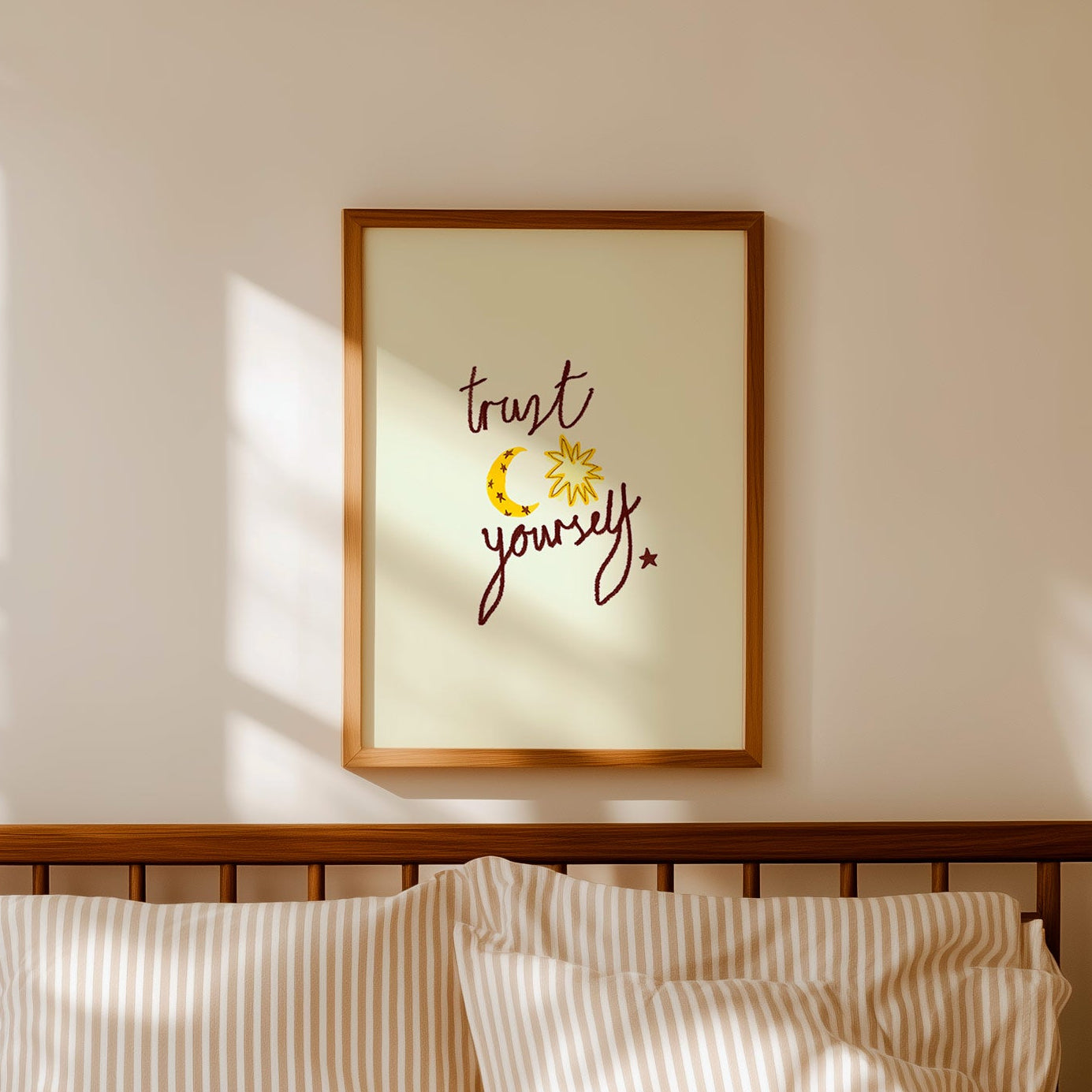 Bedroom with striped bedding, wooden headboard, and framed artwork on the wall with words 'trust yourself' on print